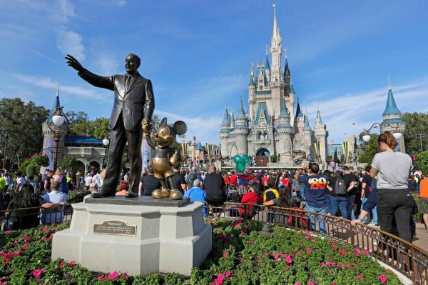 Guests watch a show near a statue of Walt Disney and Mickey Mouse in front of the Cinderella Castle at the Magic Kingdom at Walt Disney World.