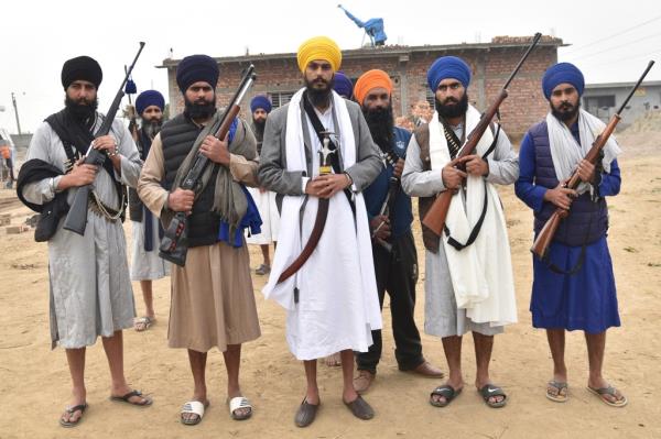 Singh, canter in yellow turban, stands outside a house with his supporters in the village Jallupur Khera, near Amritsar, India, Saturday, Jan.7, 2023.